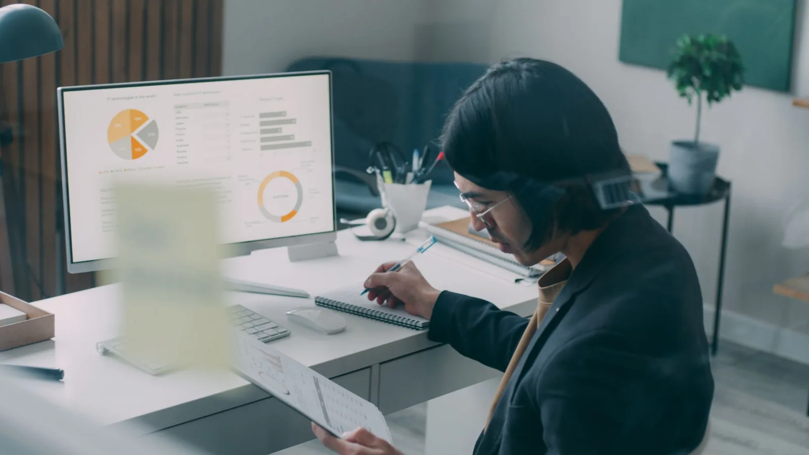 A person at a desk checks charts on a monitor and writes notes while reviewing the results.